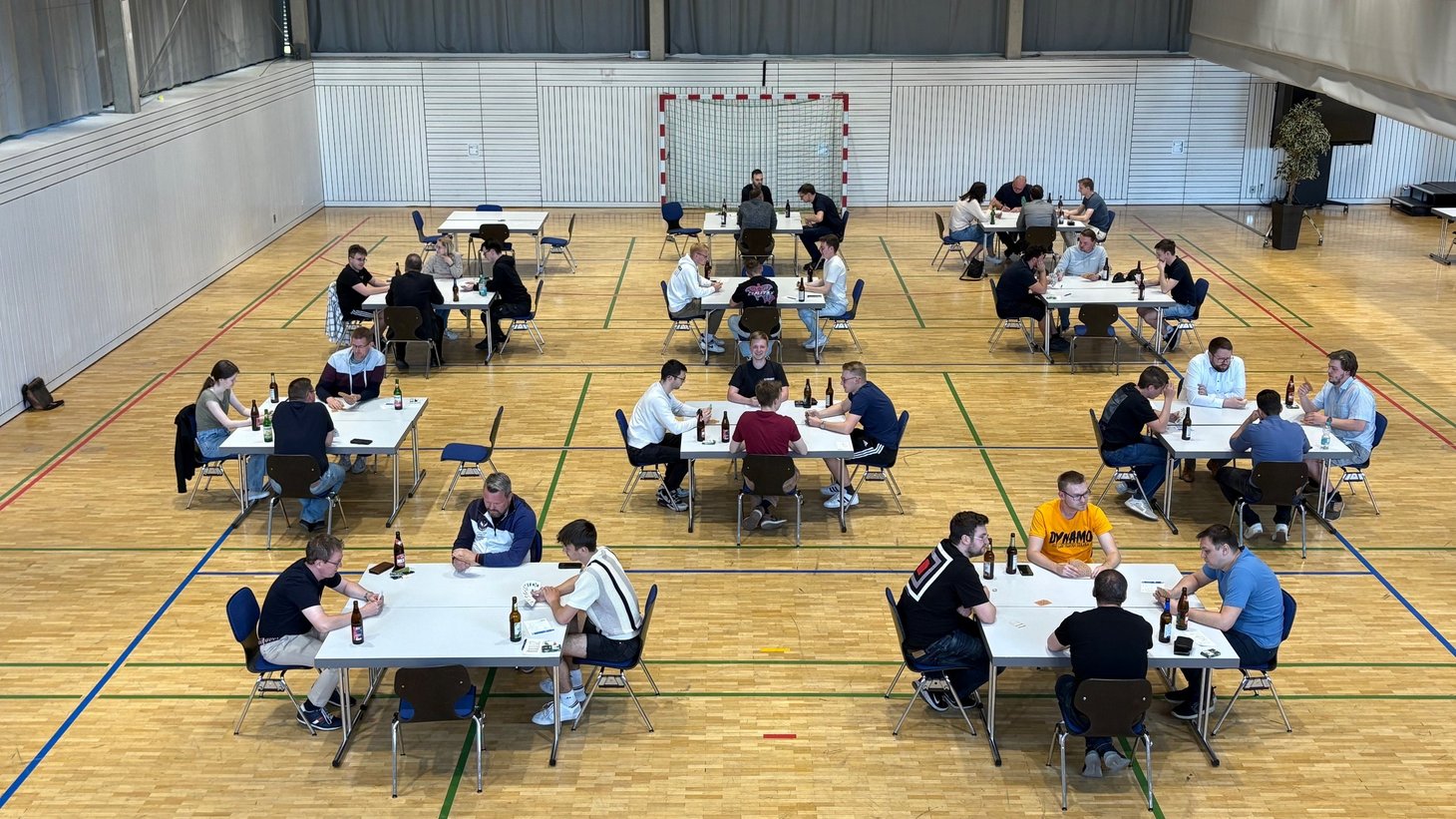 Teilnehmer des Skatturniers sitzen in der Mehrzweckhalle an Tischen