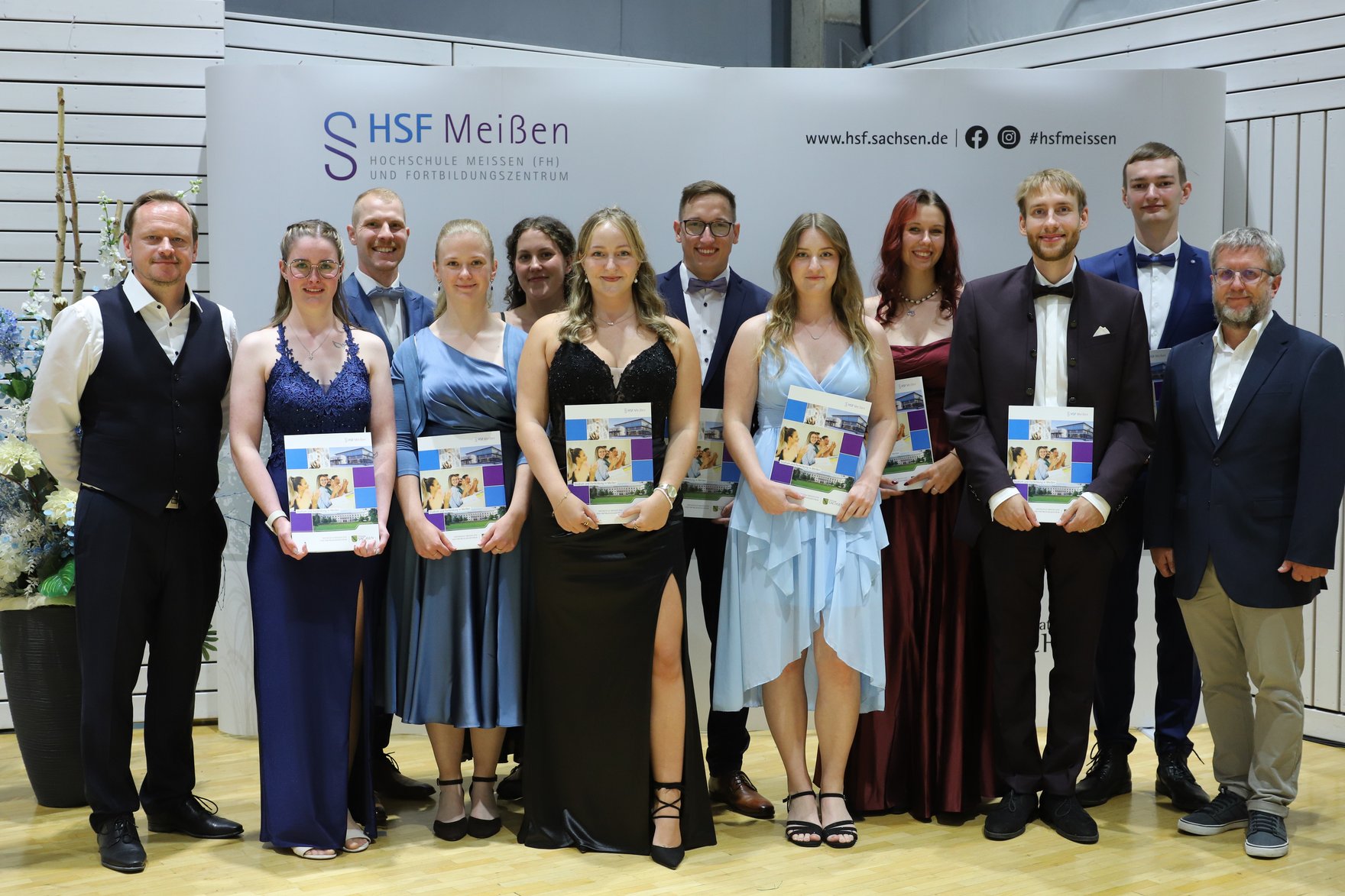 Gruppenfoto vor Fotowand der HSF Meißen mit Absolventinnen und Absolventen des Studiengangs "Sozialversicherung" und Vertretern der DRV