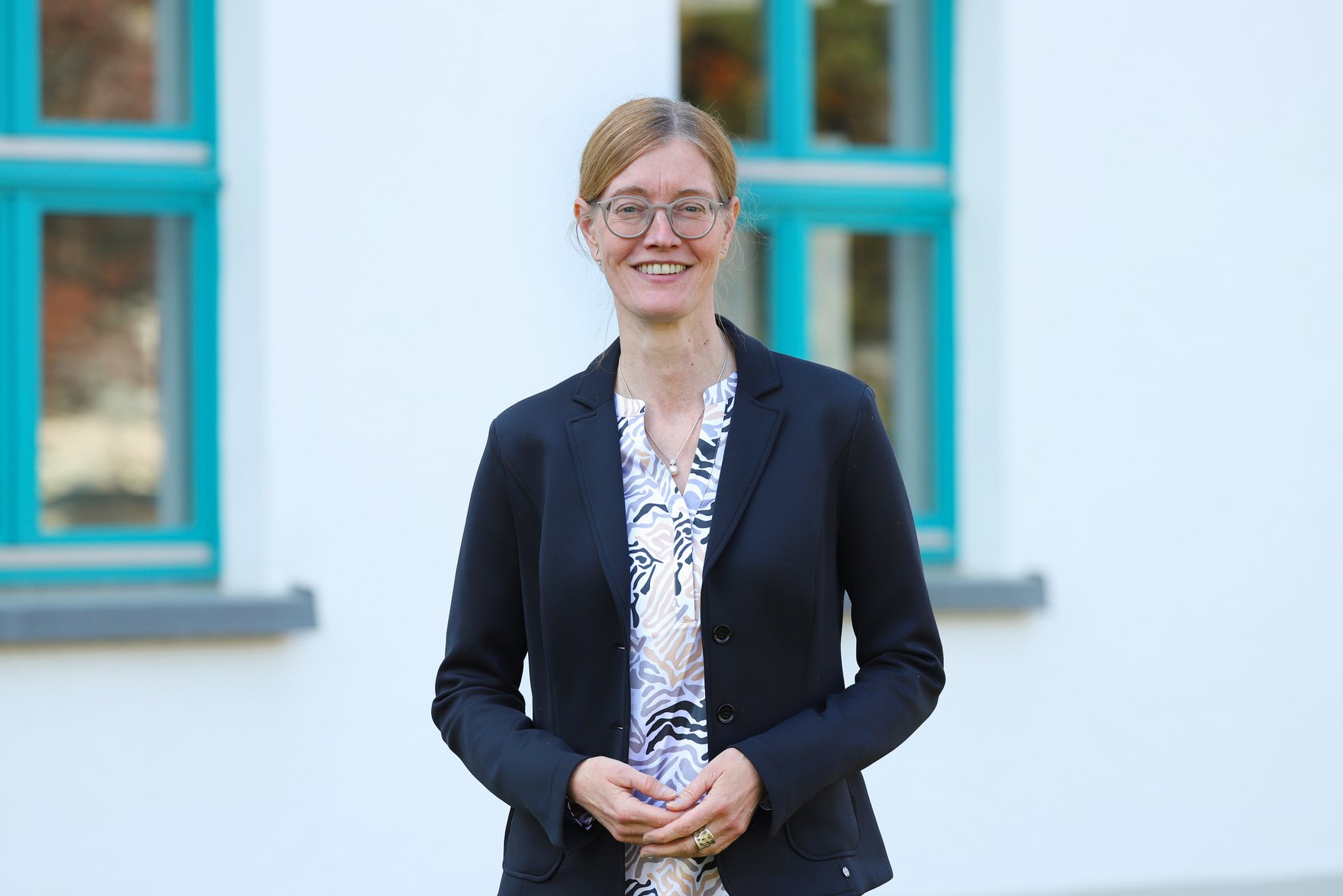 Frau Prof. Dr. habil. Mandy Hommel steht vor Haus 1 des Campus der HSF Meißen.