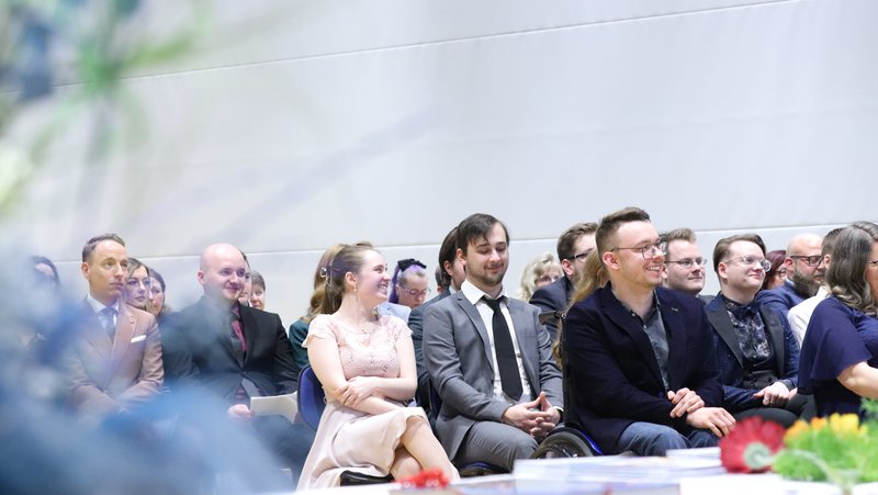 Absolventinnen und Absolventen des Studiengangs Digitale Verwaltung sitzen in Reihen bei der Zeugnisübergabe